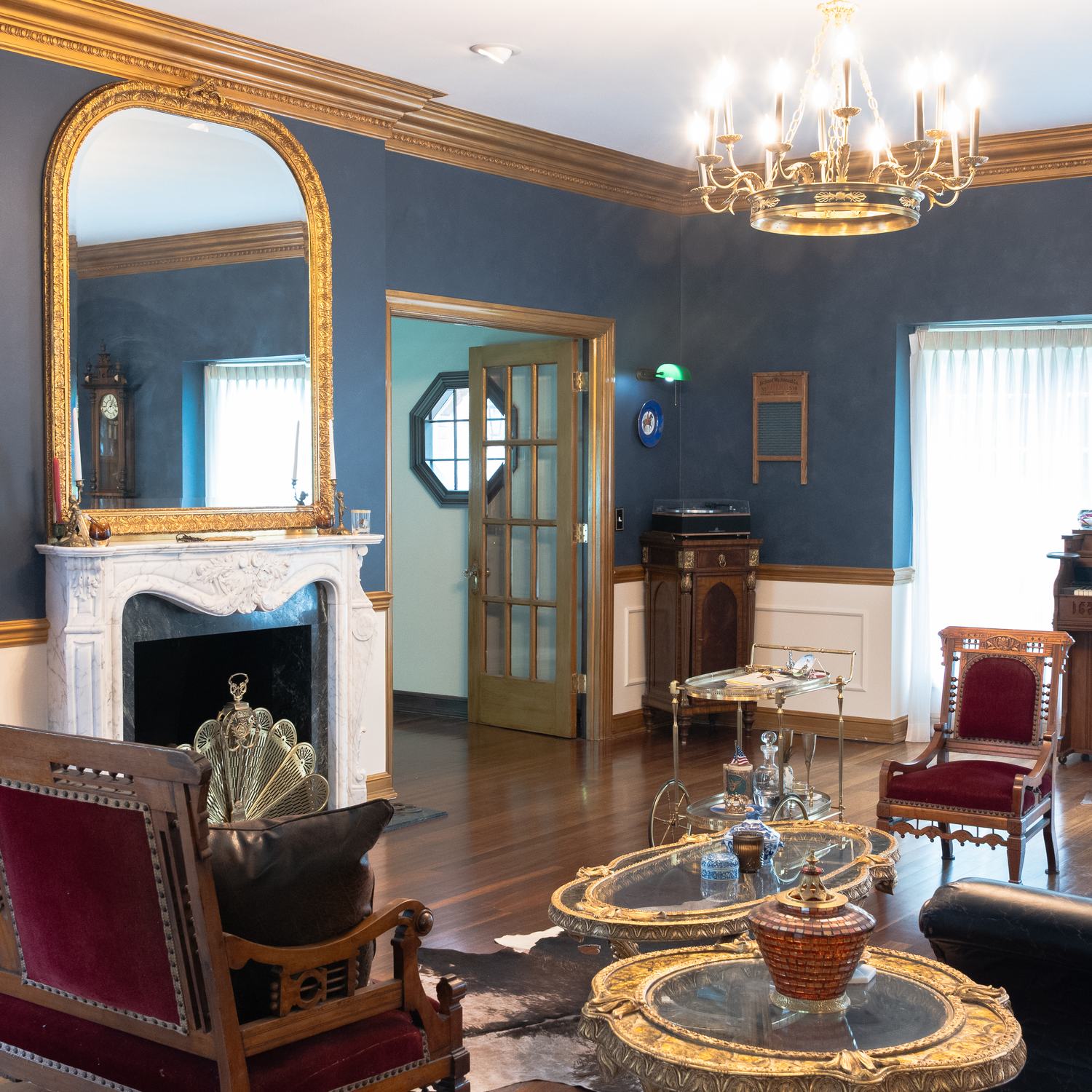 The navy drawing room with a marble fireplace and chandelier